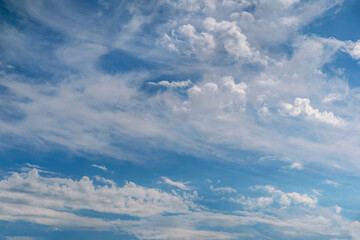Wide view of blue sky with soft white clouds drifting gently across the frame. Concept of freedom, open space, peaceful atmosphere. Natural background