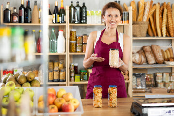Friendly female seller offers to buy canned beans in interior of a grocery supermarket