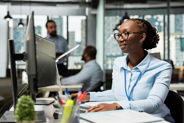 Risk analyst in office using PC to evaluate trading strategies, minimizing losses. African american...