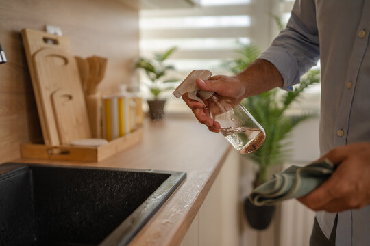 Man cleaning kitchen counter with spray bottle