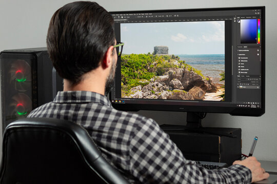 a man backward editing a professional photo into adobe photoshop sofware in a computer