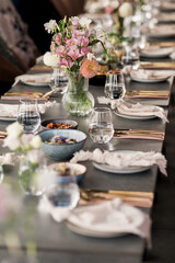 An elegant dining table beautifully set with flowers, gold cutlery, and artisanal dishes — a perfect setting for a refined gathering or celebration.
