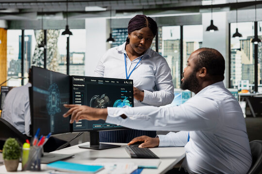 Coworkers in office using AI to review turbine data on computer to save energy and lower costs. Engineers use deep learning in office brainstorming ways to reduce turbine environmental impact