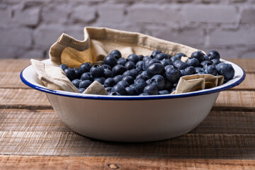 Blueberries in an enamel bowl with a cloth napkin.