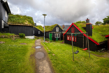 Traditional turf-roofed houses with red details and swing set