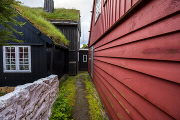 Narrow passage between red and black turf-roofed wooden houses
