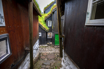 Narrow cobblestone passage with traditional turf-roofed wooden houses