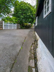 Quiet residential street with traditional black wooden house and white gate