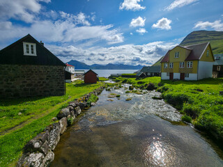 Scenic village with colorful houses and river flowing toward the fjord