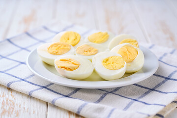 hard-boiled eggs in a plate on a light kitchen table, selective focus.