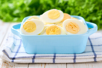 Boiled eggs in a bowl on a light kitchen table, selective focus.