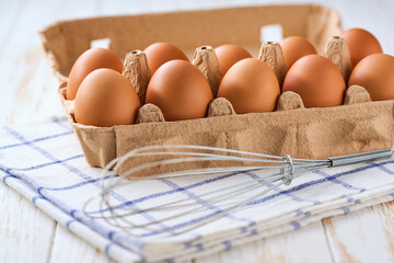 chicken eggs in a carton box on a light kitchen table, selective focus.