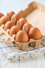 Organic eggs in a cardboard box on a white table, selective focus.