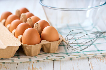 Whisking eggs. Whipped raw eggs in a bowl with whiskfresh chicken eggs on a light kitchen table, selective focus.