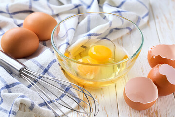 Breakfast preparation. Omelet recipe.  Whisk raw eggs in a bowl on a white table.