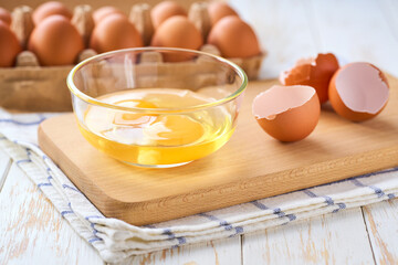 Cracked raw eggs on a light-colored kitchen table, selective focus.