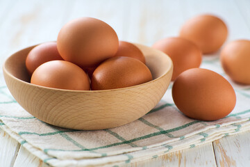 raw organic eggs in a bowl on a white table, selective focus.