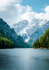 Peaceful alpine lake surrounded by pine forests and dramatic snow-covered mountain cliffs