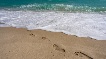 Foot steps on sand. Tropical coastline. Exotic sea beach destination. Foamy sea beach waves. Sunny sea beach holiday. Relaxing sea beach vacation.