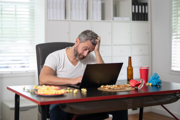 A man suffers from a headache on morning. Tired employee holds his head due to a morning headache. Middle-aged businessman struggles with headache. Office worker feels pain from a headache.