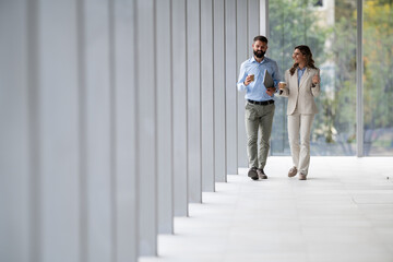 Business colleagues walking and talking in office hallway