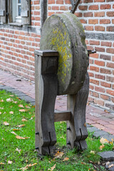 Alter Schleifstein vor historischem Fachwerkhaus