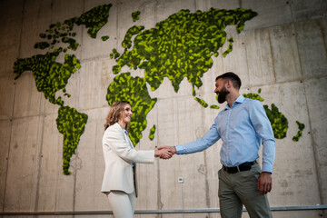 Business partners shaking hands on green world map background © Zoran Jesic
