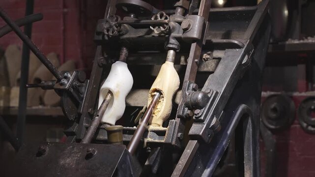 Industrial copy lathe shaping a wooden clog from raw block by following plastic mold with rotating cutters, traditional Dutch shoes