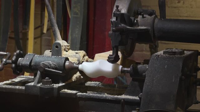 Industrial copy lathe shaping a wooden clog by tracing mold contours with rotating blades and flying sawdust