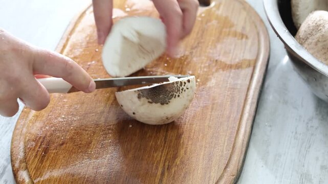 woman cutting with knife parasol mushrooms in kitchen