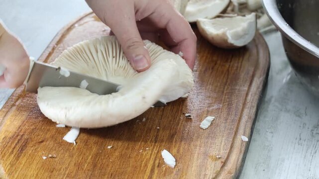 woman cutting with knife parasol mushrooms in kitchen