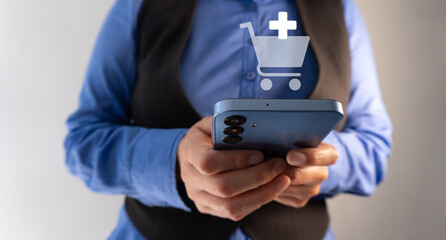 Adding products to the shopping cart. Businesswoman holding a smartphone with a shopping cart with a plus sign.