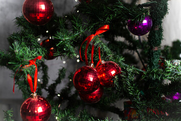 closeup view of red christmas ornaments on a green tree, red Christmas decorations on a christmas tree, sparkly textured red christmas tree baubles on artificial tree