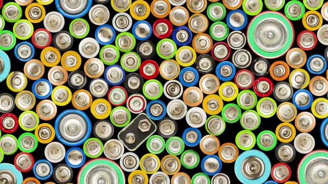 Top-down view of assorted batteries in various sizes and colors, arranged tightly with visible terminals against a black background, symbolizing energy, power, and recycling themes.