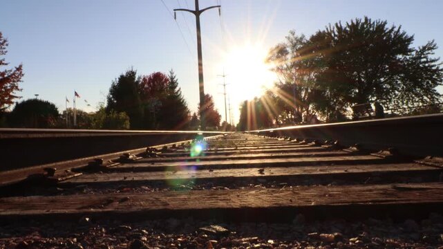 4K tilting shot of a railroad with the sun high in the sky. 
