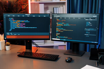 Programming code on computer two screens on desktop placing working desk showing intelligent...