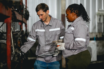 Diverse technician checking used car damaged engine block at scrap yard warehouse recycle area part. Maintenance engineer inspecting rust oily auto motor old spare part in junkyard for reuse service