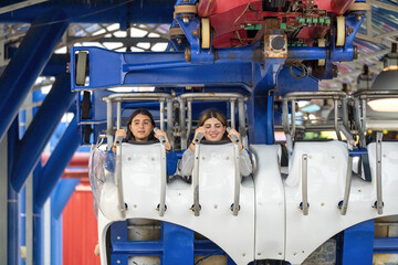 Young women laughing and anticipating a roller coaster experience with joy and excitement