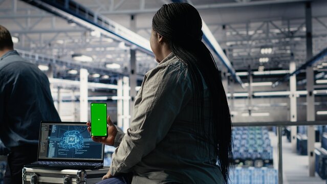 Data center admin uses isolated screen smartphone while deploying machine learning tech. Server room IT expert uses chroma key phone while training artificial intelligence systems with datasets - Powered by Adobe