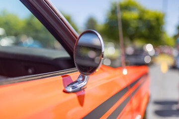 Side view mirror of orange vintage car close up view , Shallow depth of field.