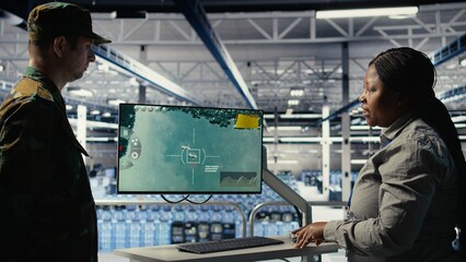 Military data center coworkers looking at radar software on screen to watch for enemy threats. Team...