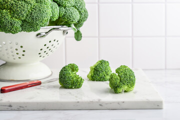 Raw broccoli in a white enamel colander