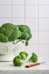 Raw broccoli in a white enamel colander