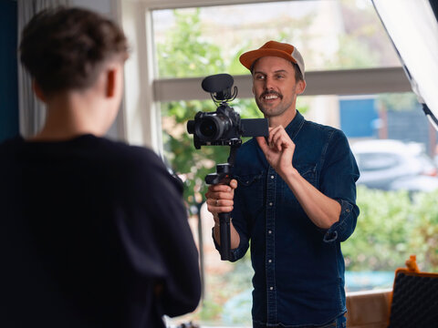 Videographer engaging with subject during interview filming session using handheld camera stabilizer