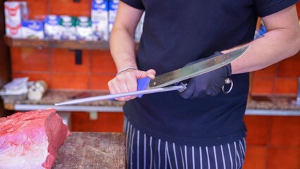 Butcher cutting fresh raw meat on wooden board in traditional butcher shop