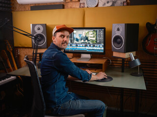 Video editor turning to camera while working at editing station with timeline visible on screen