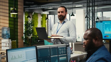 Male team leader monitoring analytics on a laptop in co working space, handling daily tasks for business productivity. Using performance metrics and other insights for development.
