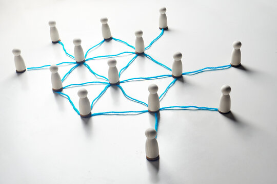 Connected wooden pegs linked by string lines, visualizing network relationships, communication channels and information flow across a system.
