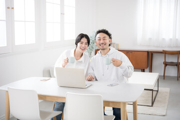 Fototapeta premium 綺麗なリビングでダイニングカメラ目線の夫婦 幸せな結婚のイメージ