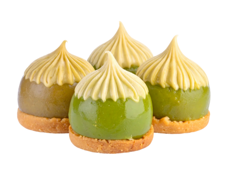 Four dome-shaped green desserts with frilly tops on tan cookie bases, isolated on black, close-up studio shot